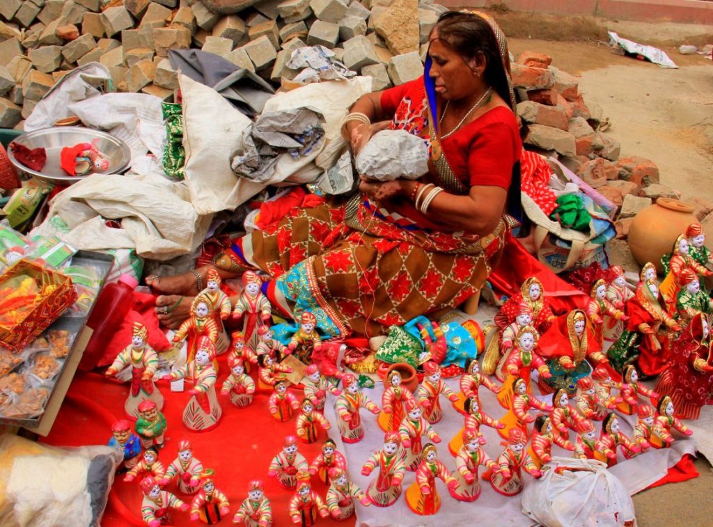 A woman paints Teej dolls for sale on Jaipur street.